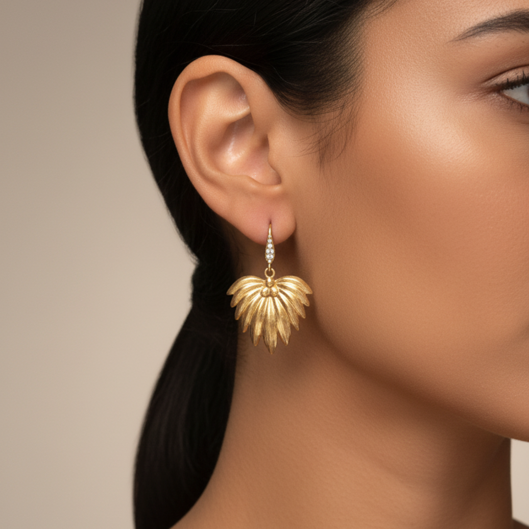 Pendientes Alas de Fénix en acabado dorado de Sfinge, fotografía profesional en oreja femenina.