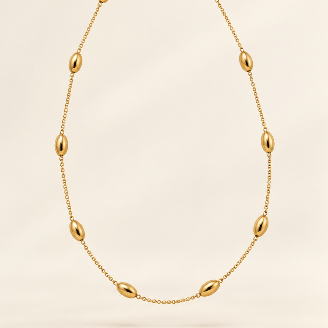 Collar Elia dorado con pequeñas bolitas ovaladas distribuidas a lo largo de una cadena fina.