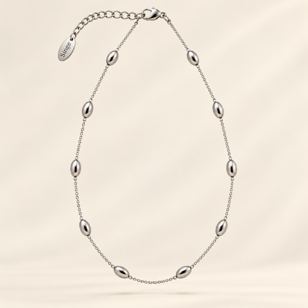 Collar Elia plateado de cadena fina con bolitas ovaladas pulidas llevado al cuello. acero plateado
