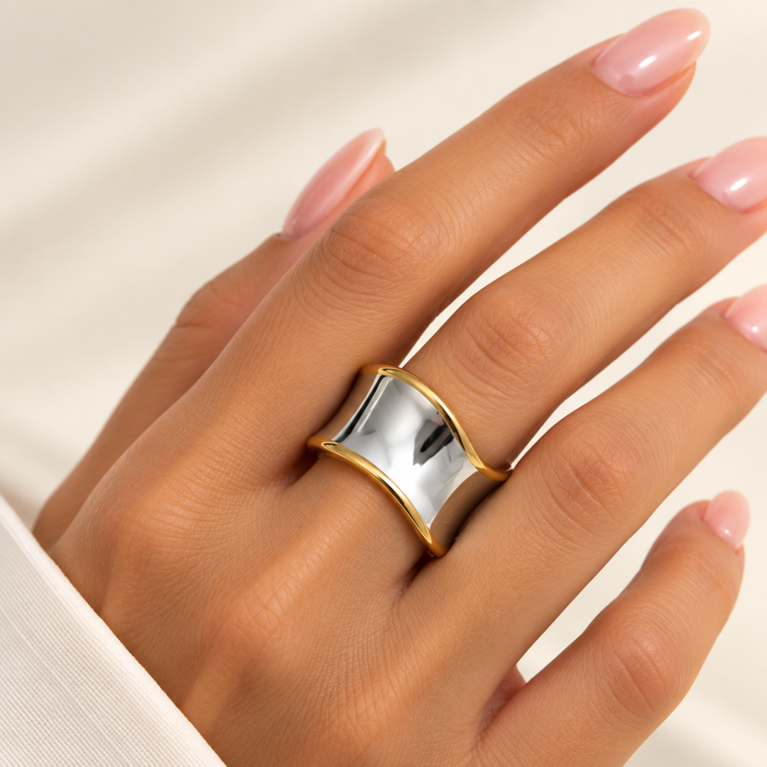 Anillo Onda bicolor de acero con bordes dorados en mano de mujer