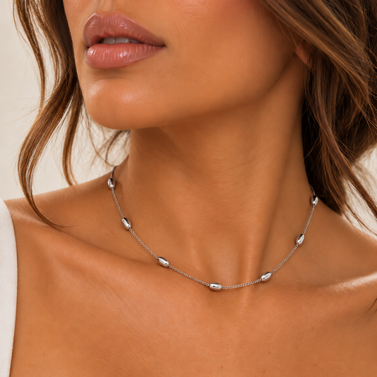 Collar Elia plateado de cadena fina con bolitas ovaladas pulidas llevado al cuello.