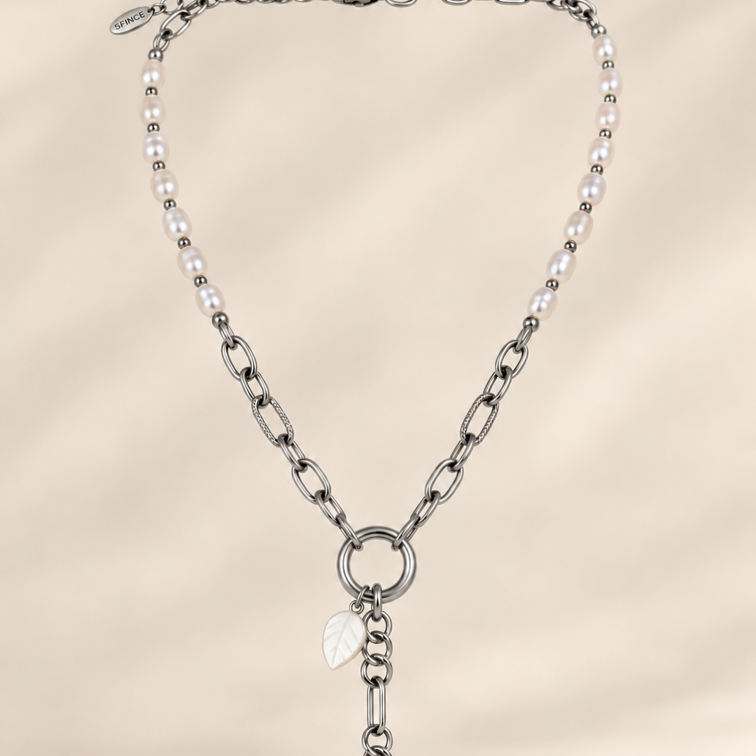 Collar Elara plateado con perlas de agua dulce, cadena de eslabones y hoja de nácar, llevado con escote blanco.

