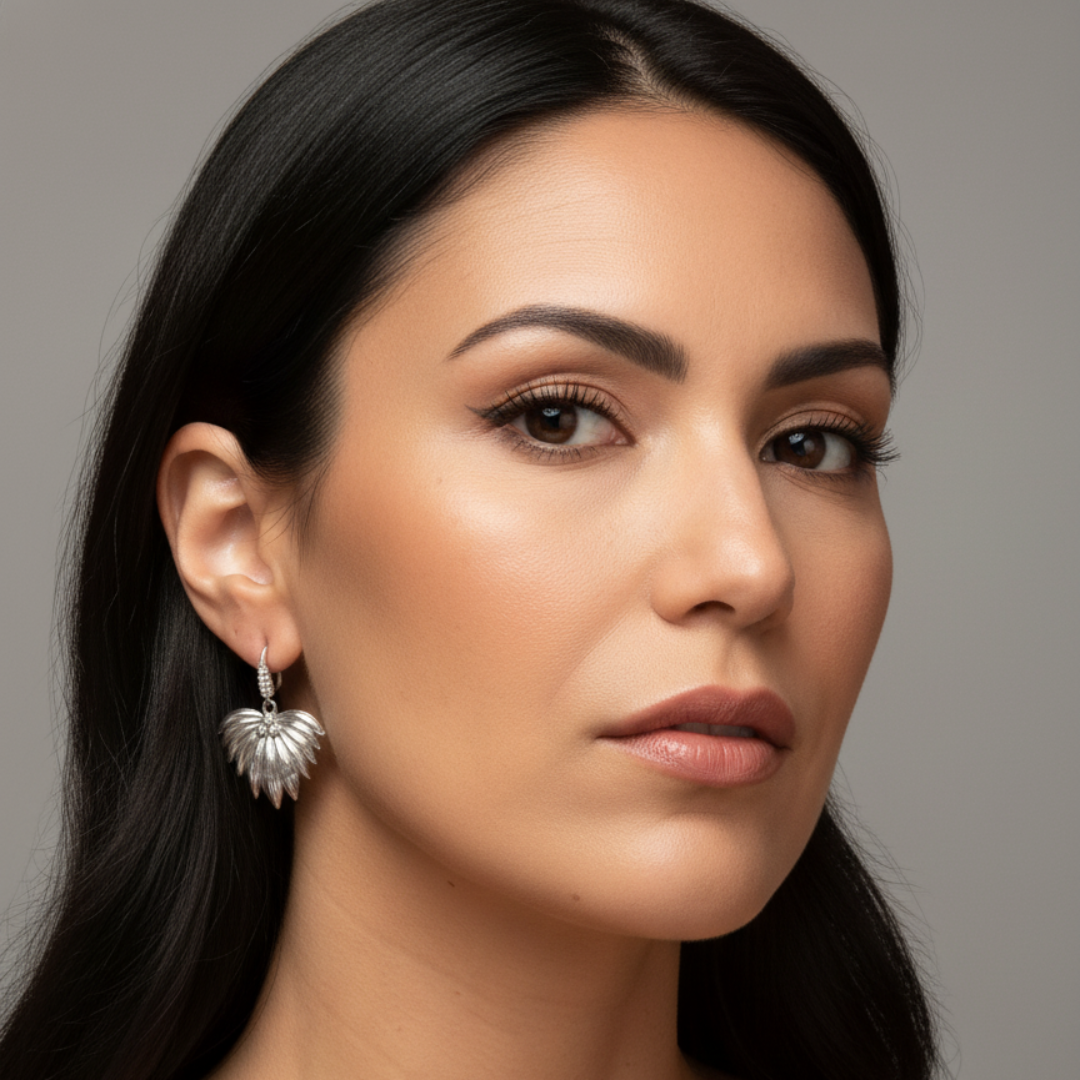 Pendientes Alas de Fénix en acabado plateado de Sfinge, mostrados en modelo mujer, detalle en oreja.